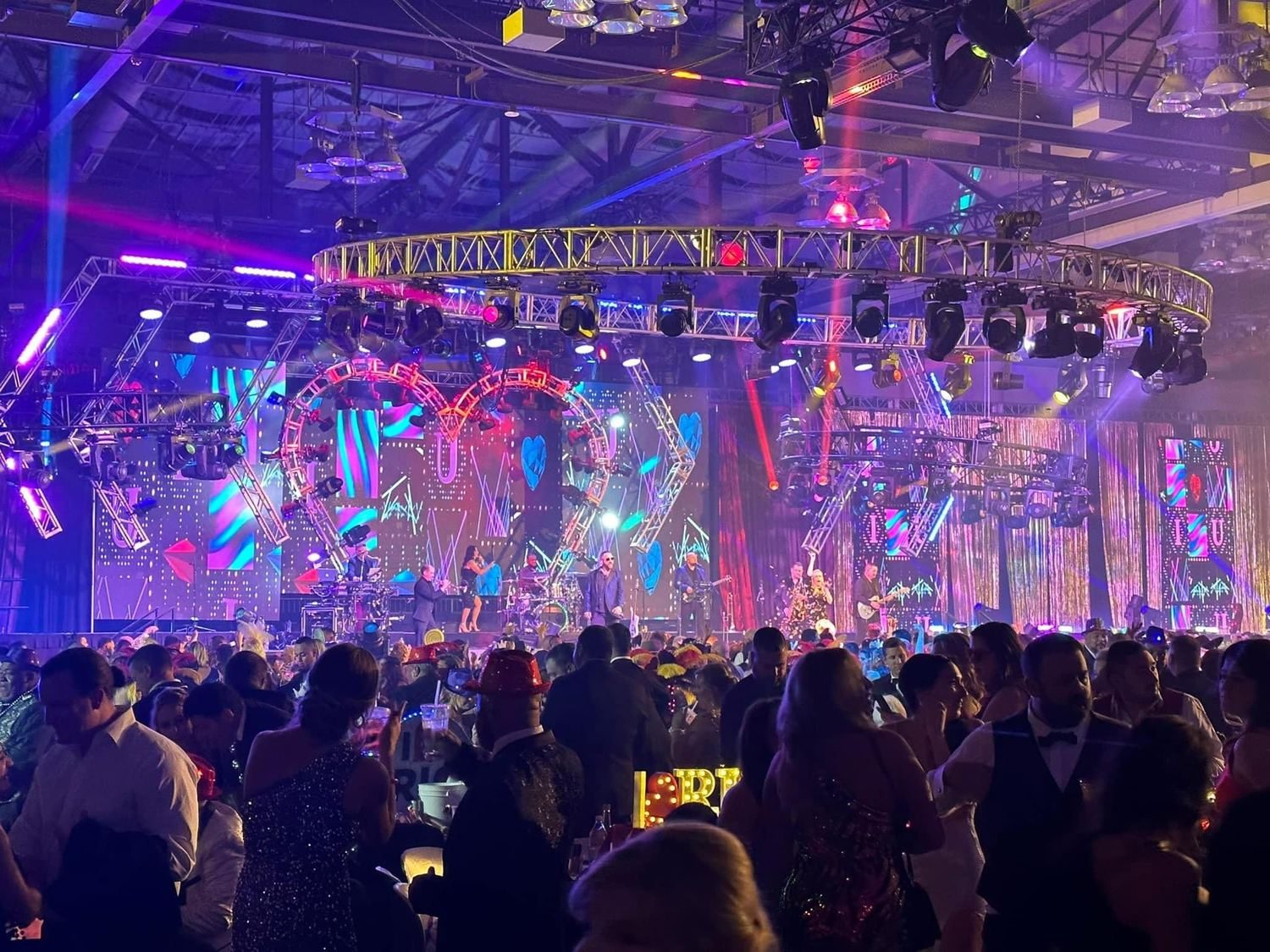 A ballroom stage dressed with colorful lighting truss and LED, the band performing to a full room.