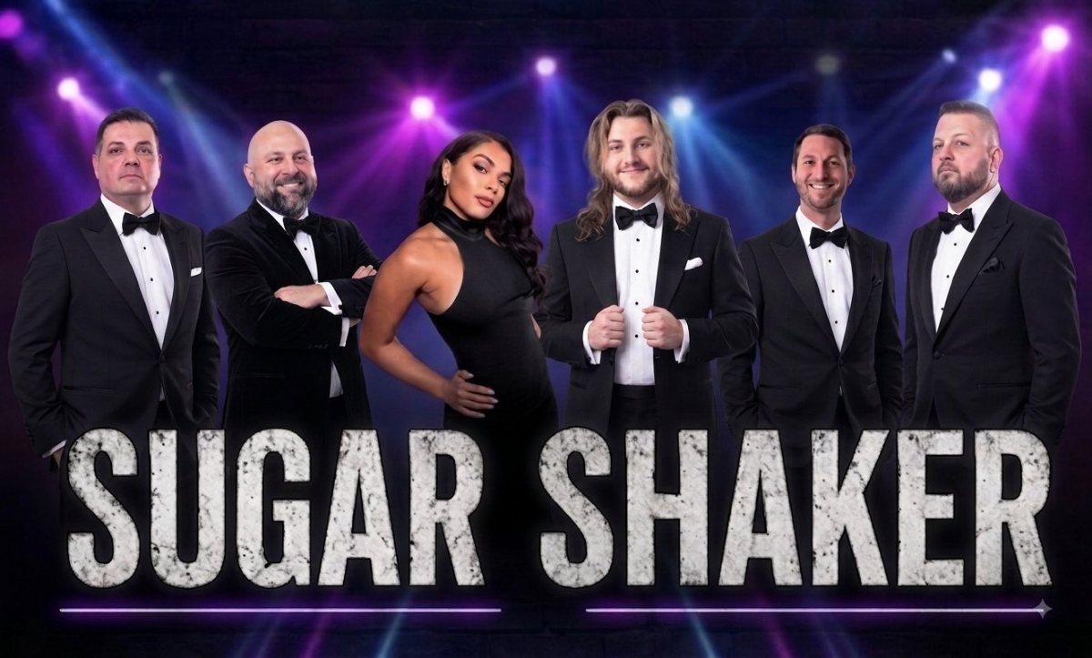 Sugar Shaker in black tie under purple stage lights.
