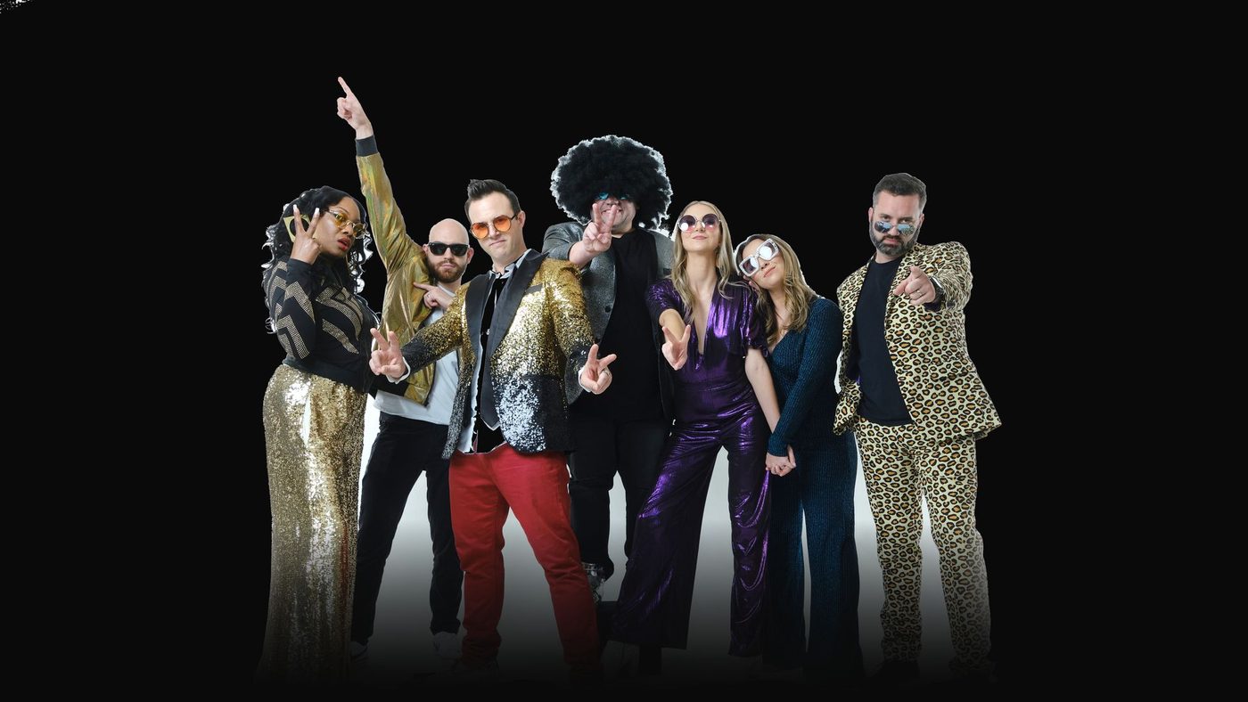 The SUPAFLY cast in gold sequins, leopard print, purple velvet and an afro, striking disco poses.